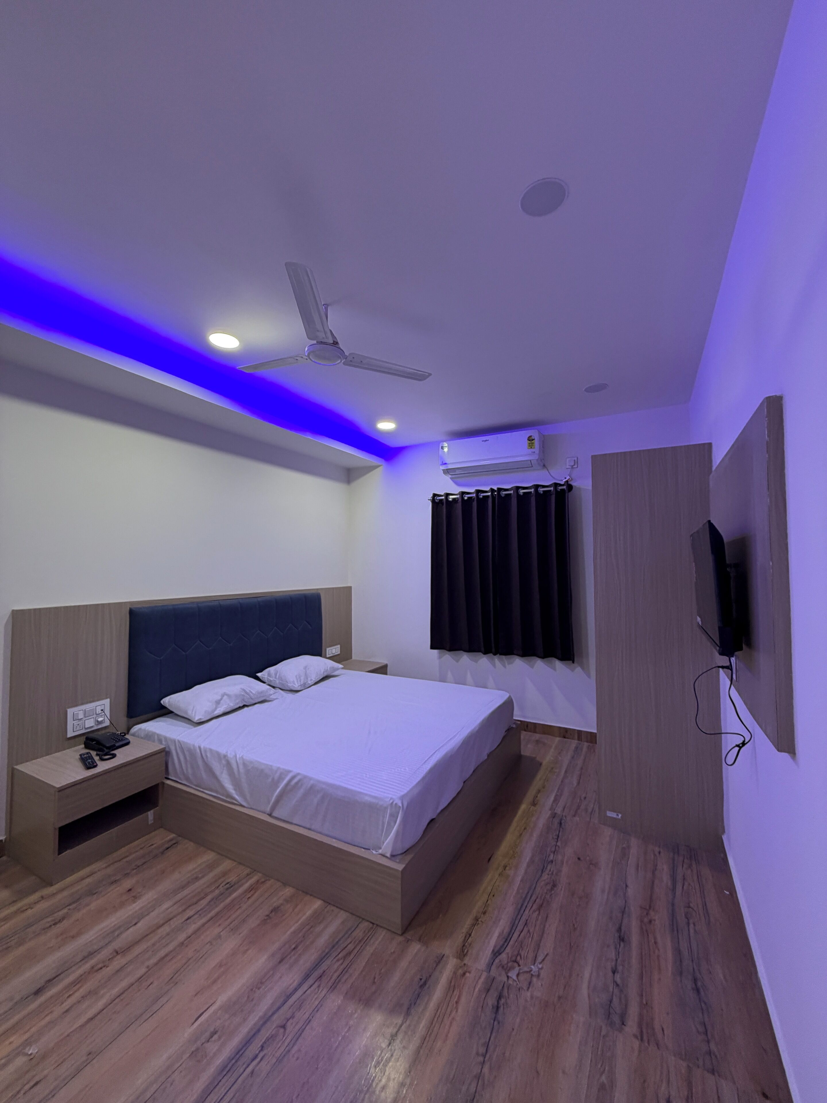 Habitación de hotel moderna con cama, mesita de noche y ventilador de techo.