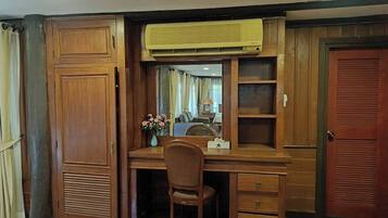 A wooden desk with a chair, a mirror, and a vase with flowers.