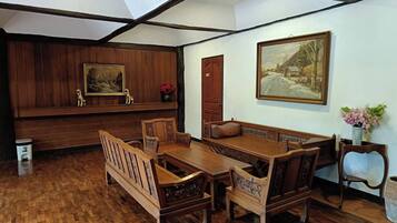 A room with a wooden dining set, a bench, and two paintings on the walls.