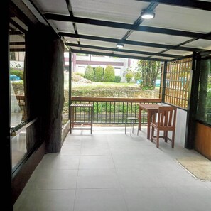 A balcony with a view of a garden and a building in the background.