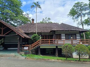A traditional wooden building with a balcony, a staircase, and a sign indicating a specific location.