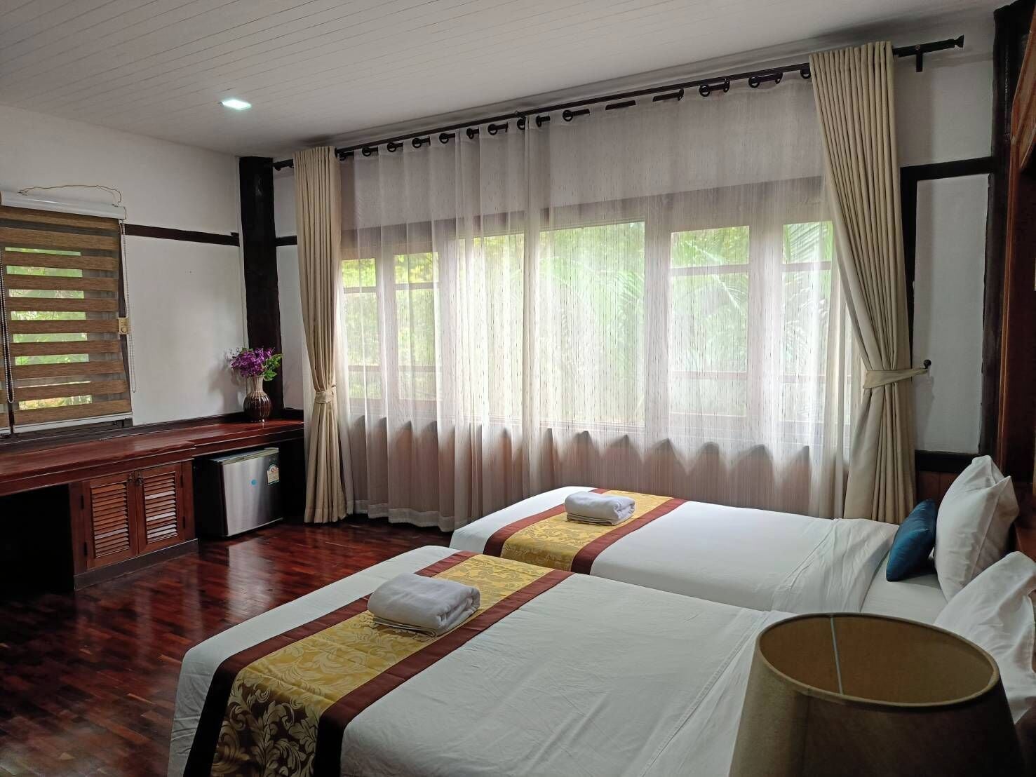 A hotel room with two beds, a desk, and a window with curtains.