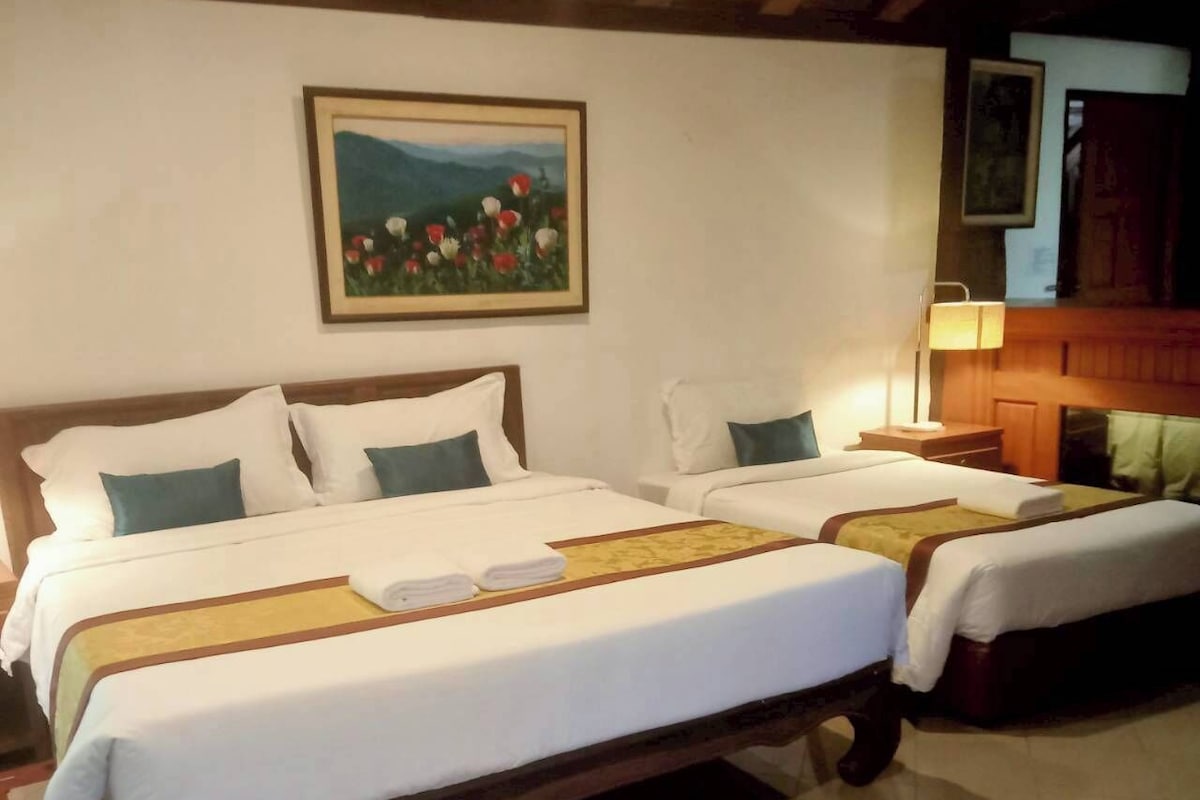 Habitación de hotel con dos camas, un cuadro en la pared y un cabecero de madera.