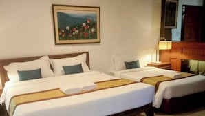 A hotel room with two beds, a painting on the wall, and a wooden headboard.