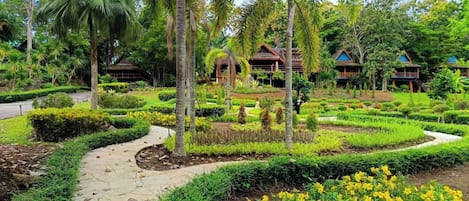 Un complexe hôtelier tropical doté d’un jardin bien entretenu, de palmiers et de villas de style traditionnel.