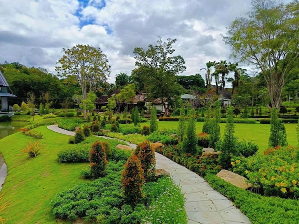 A landscaped garden with a stone pathway, various shrubs, and trees.