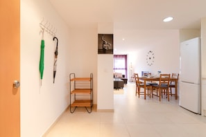 Een moderne keuken met een eethoek, een houten wandplank en een klok aan de muur.