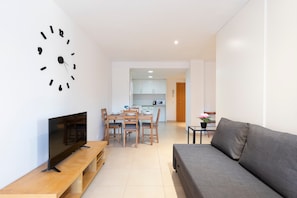 Een moderne woonkamer met een flatscreen televisie, houten meubels en een grijze bank.