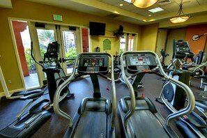 A gym with treadmills, exercise bikes, and a large window with a view of greenery. - Orlando | Pool & Disney Access | 3BR Sleeps 10 (Lake Buena Vista)
