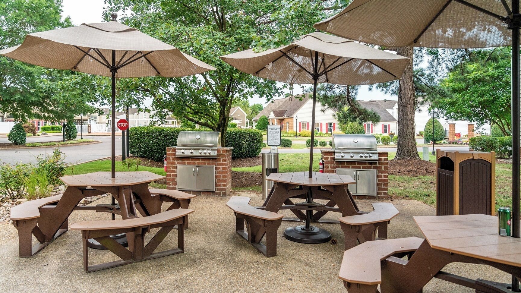 An outdoor patio with picnic tables and barbecue grills.
