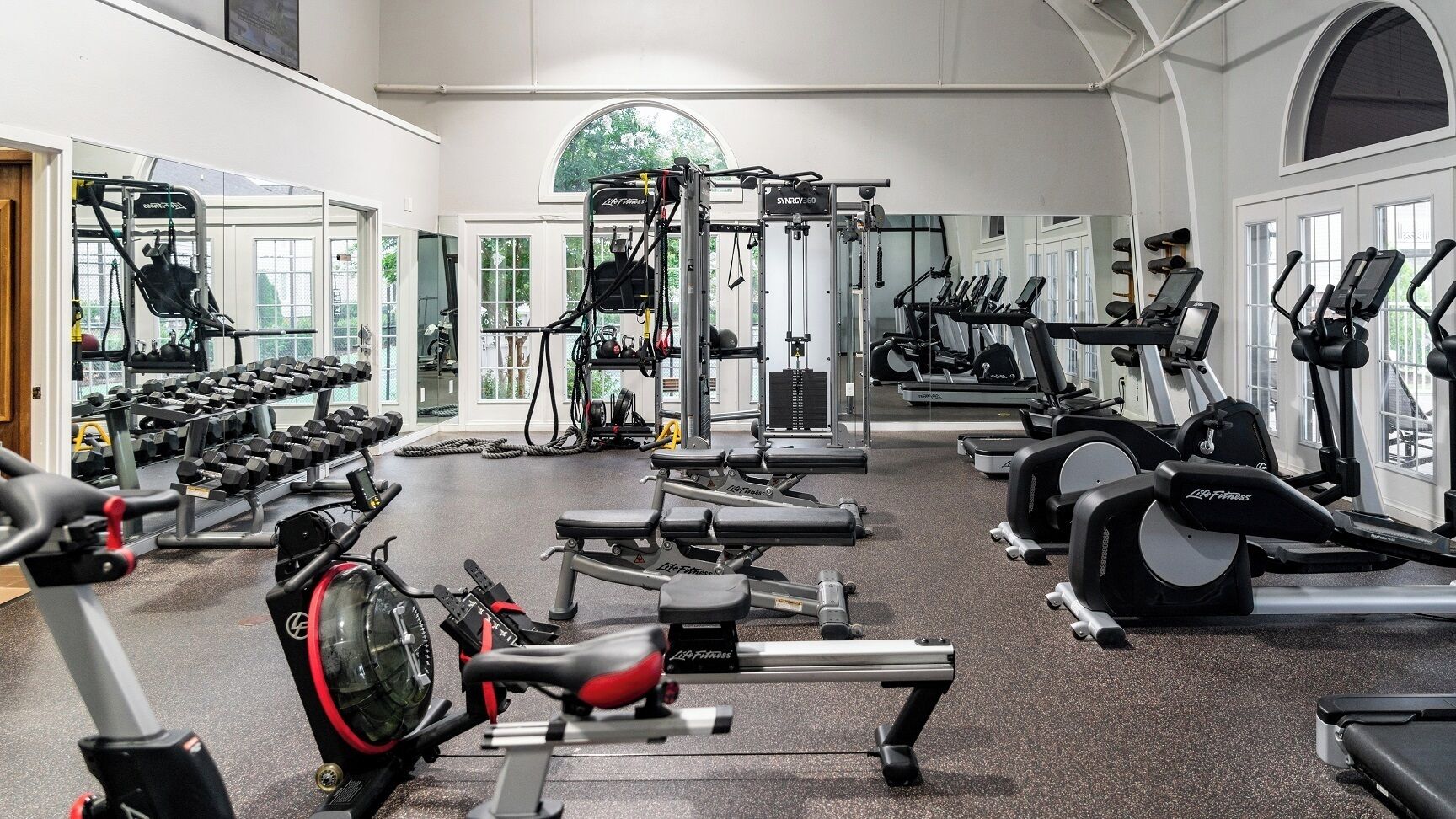 A gym with various exercise equipment including treadmills, elliptical machines, and weight machines.