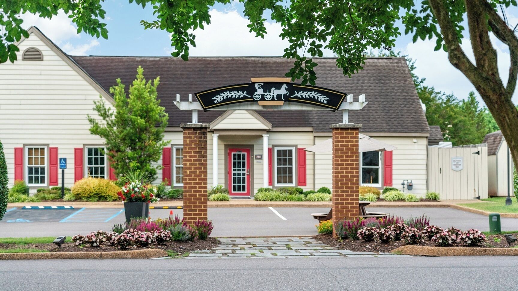 A building with a sign featuring a horse and carriage, a brick entrance, and a red door.