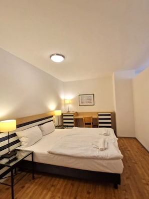 Ein Hotelzimmer mit Bett, Nachttischen, einem Schreibtisch und einem Stuhl.