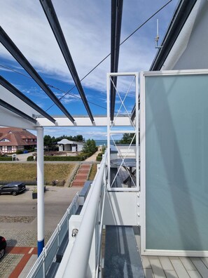 Ein Balkon mit Blick auf ein Wohngebiet, darunter Häuser und ein Auto.
