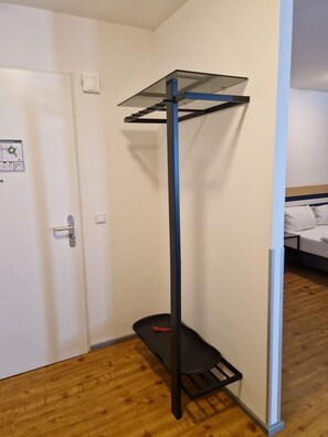 Een kamer met een deur, een bed en een metalen schapkas met een glazen bovenblad.
