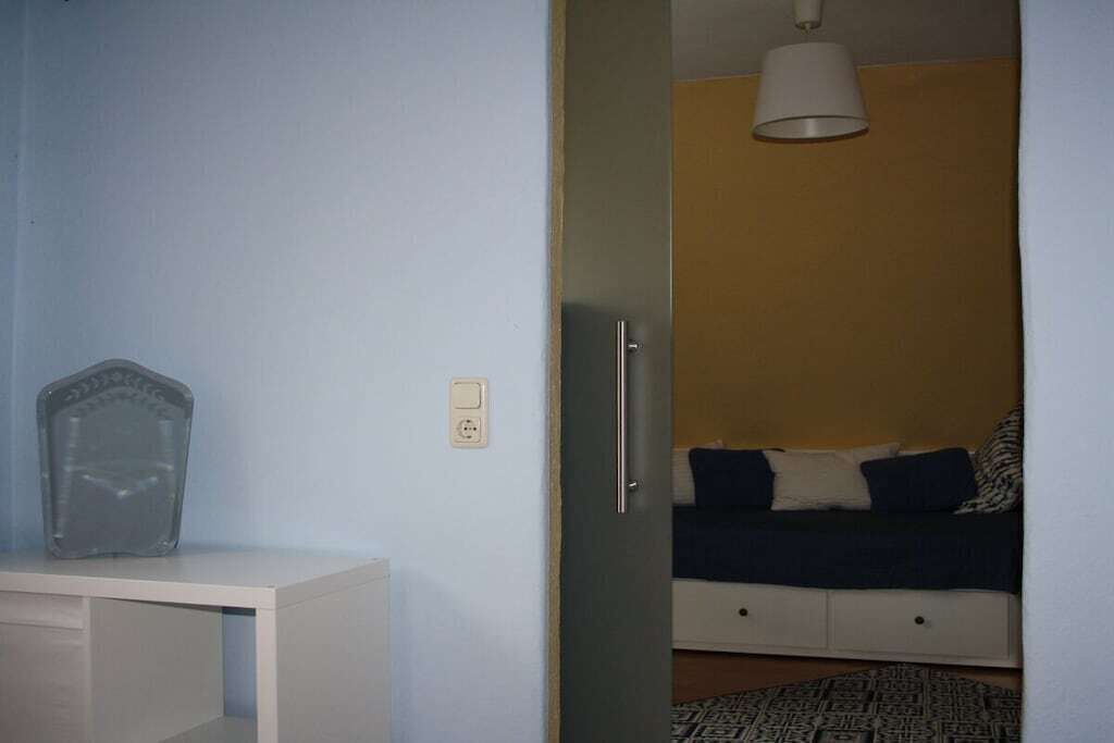 Quarto com cama, mesa de cabeceira, luminária e tomada.