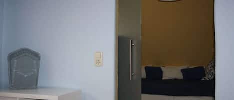 Quarto com cama, mesa de cabeceira, luminária e tomada.