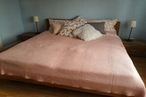 Een bed met een geruit sprei, meerdere kussens en twee bedlampen.