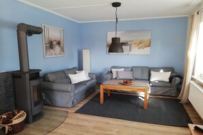 En stue med sofasæt, et bord, en pejs og kunst på væggene.