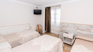 A hotel room with two beds, a TV mounted on the wall, a chair, a small table, and a window with curtains. - HOSTAL VIKY (Madrid)