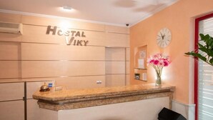 A reception desk with a clock and a vase of flowers. - HOSTAL VIKY (Madrid)