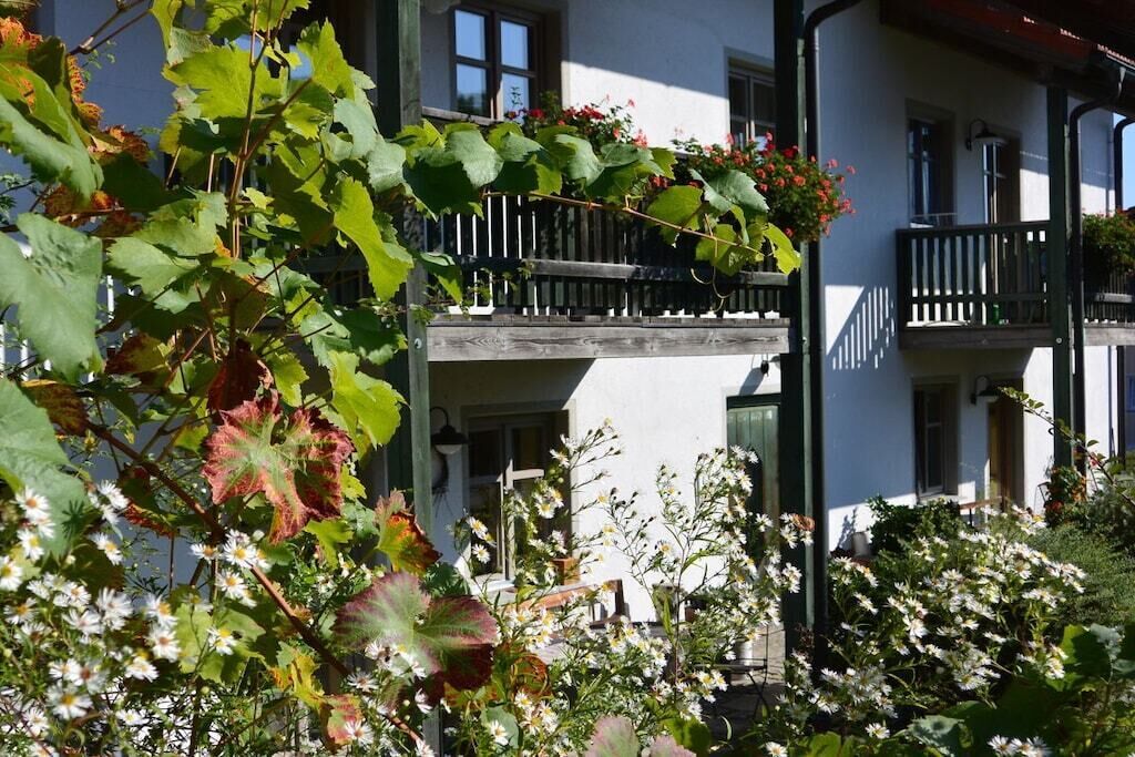 Un edificio con balcones, un jardín con flores y un cielo despejado.