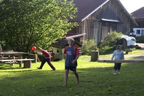 Une grange en bois avec un toit en pente, une table de pique-nique et un arbre au premier plan.