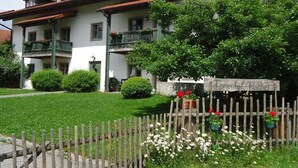 Un bâtiment à deux étages doté d’un balcon, d’une clôture en bois ornée de fleurs et d’une enseigne sur laquelle on peut lire « Jelenhof Fischer ».