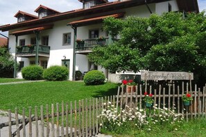 Ein zweigeschossiges Gebäude mit einem Balkon, einem Zierzaun mit Blumen und einem Schild mit der Aufschrift 'Jelenhof Fischer'.