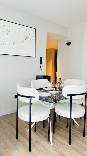 A dining area with a round table, white chairs, and a framed artwork on the wall.