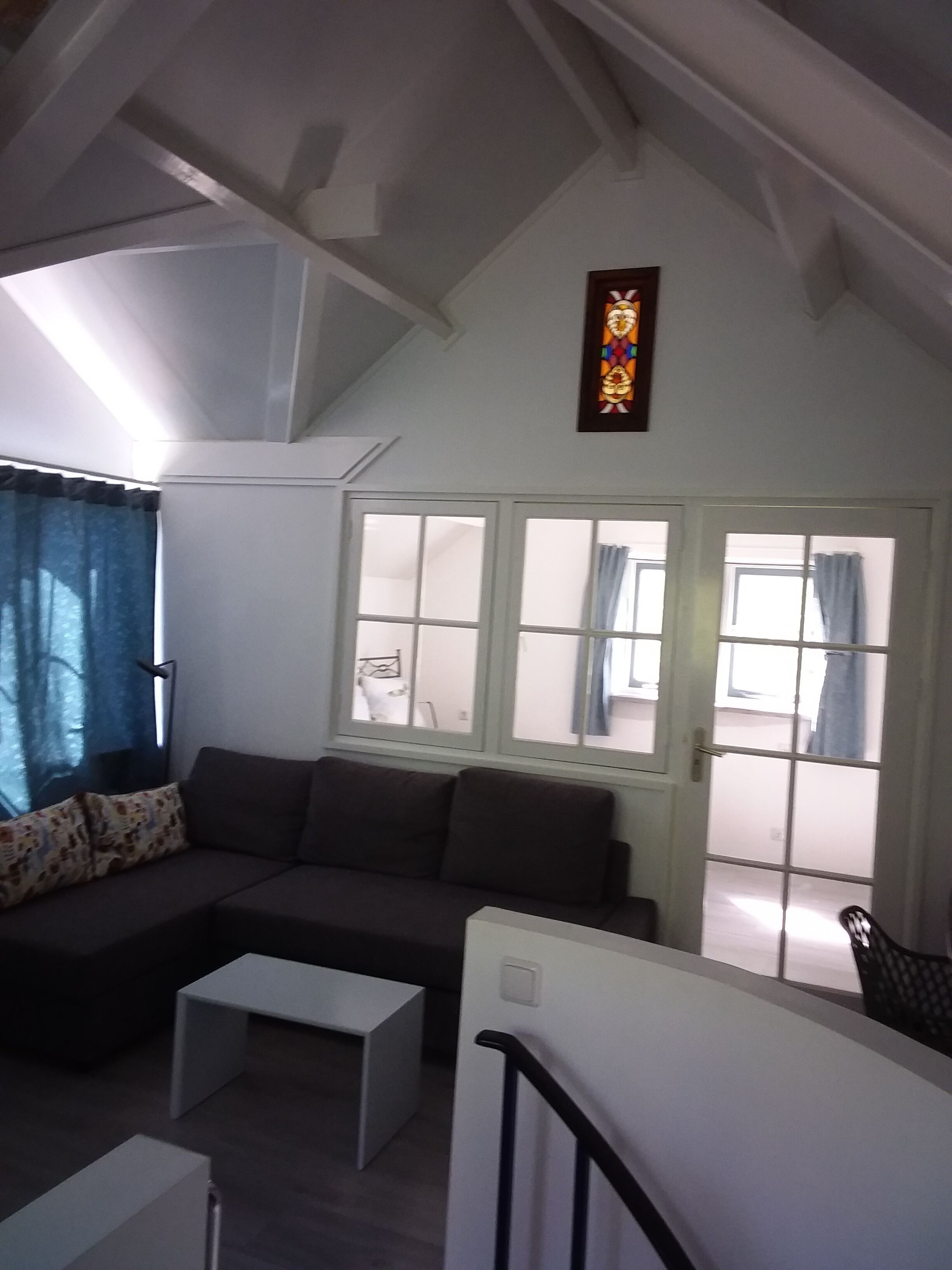 Een woonkamer met een hoekbank, een kleine witte tafel en een trap naar een bovenverdieping.