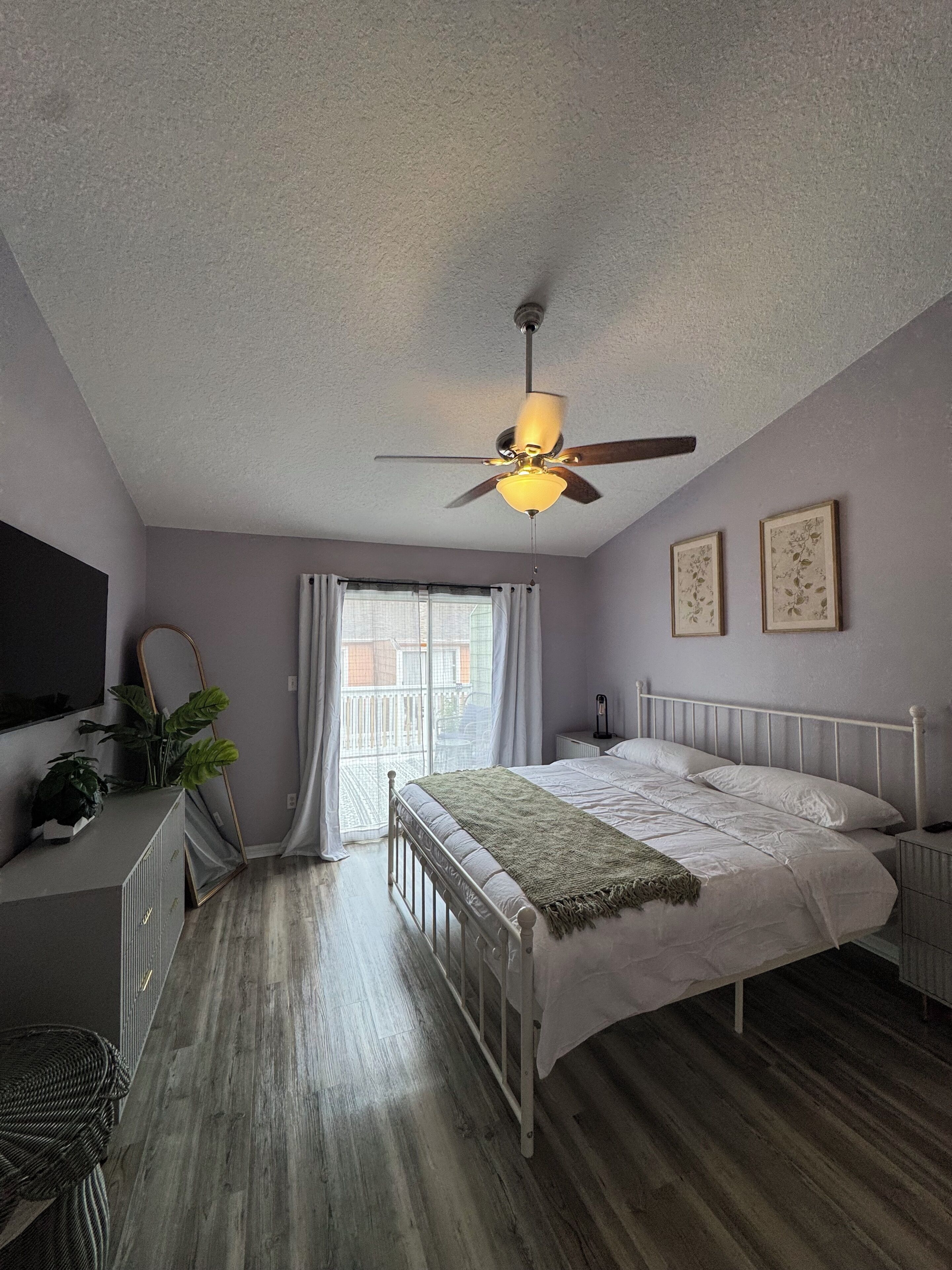 A bedroom with a bed, bedside table, and a ceiling fan.