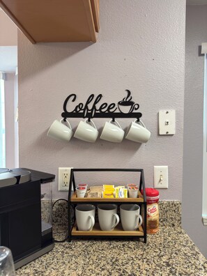 Una cocina con un soporte para tazas de café, una cafetera y un dispensador de granos de café.