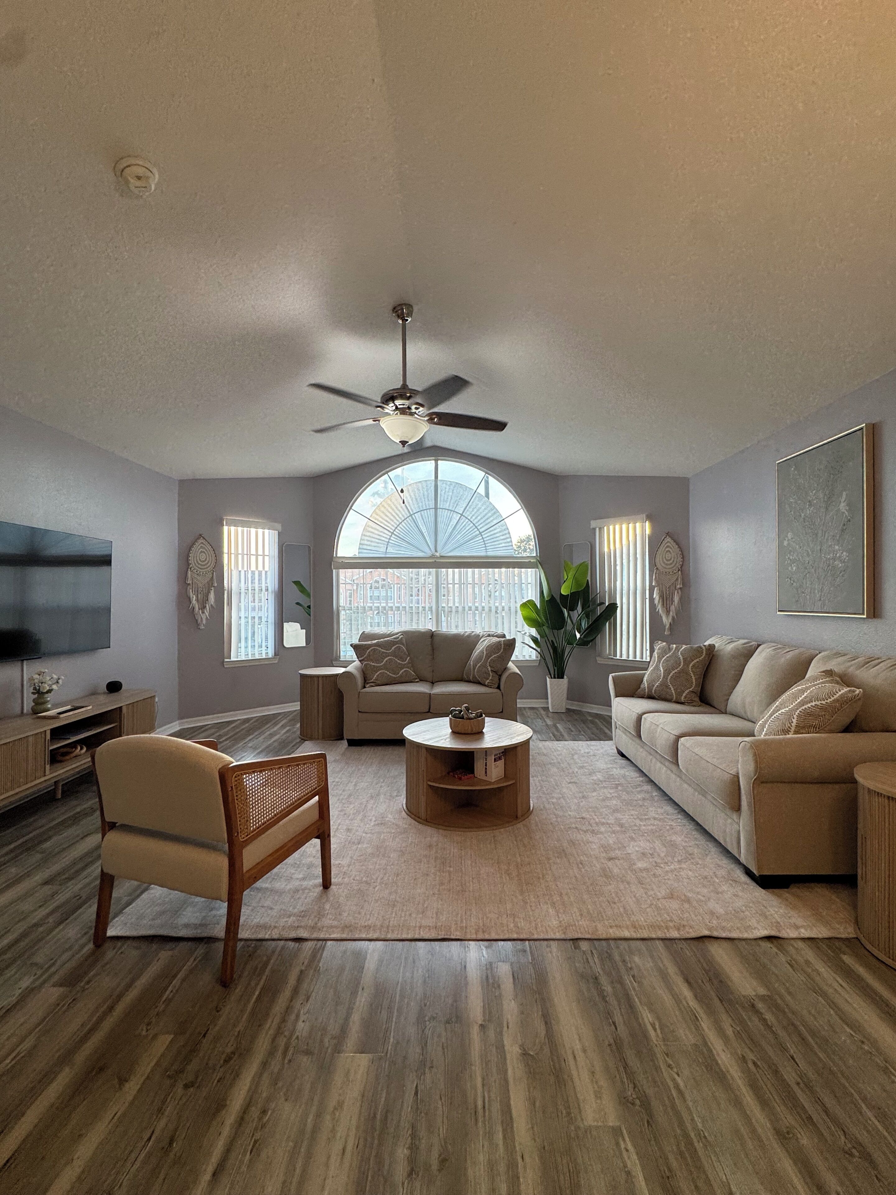 A living room with a ceiling fan, two sofas, a coffee table, and a TV.