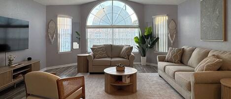 A living room with a ceiling fan, two sofas, a coffee table, and a TV.