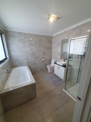 Un baño moderno con bañera, inodoro y zona de ducha.
