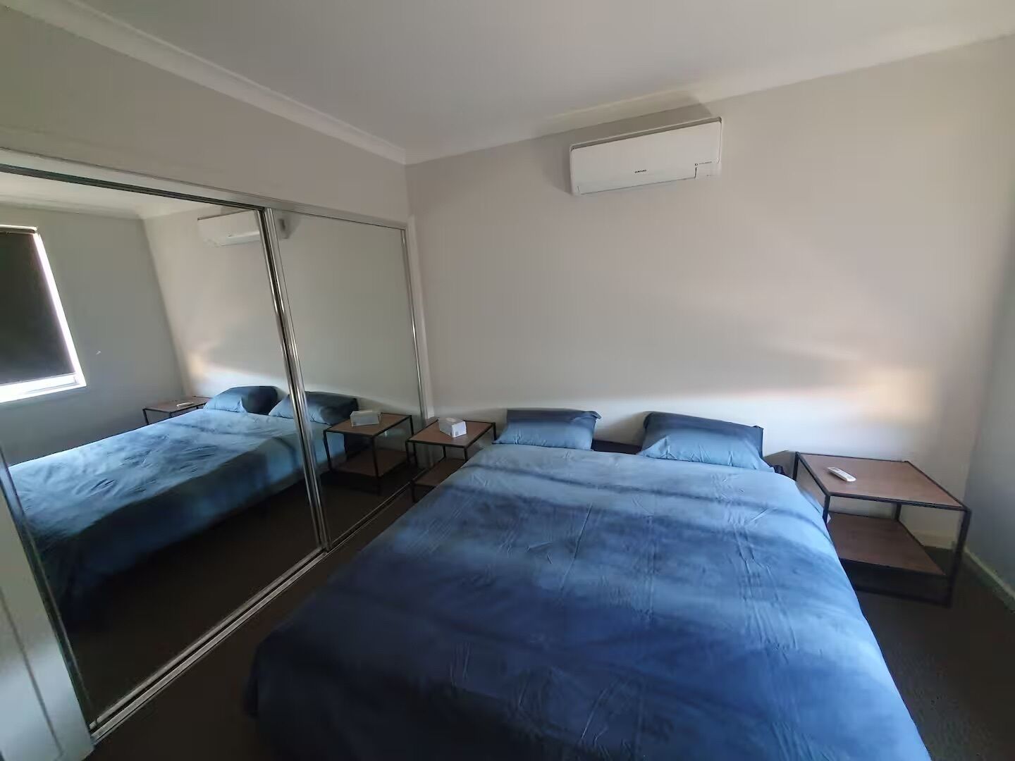 Una habitación de hotel con una cama grande, una mesita de noche, una pequeña mesa y un espejo.