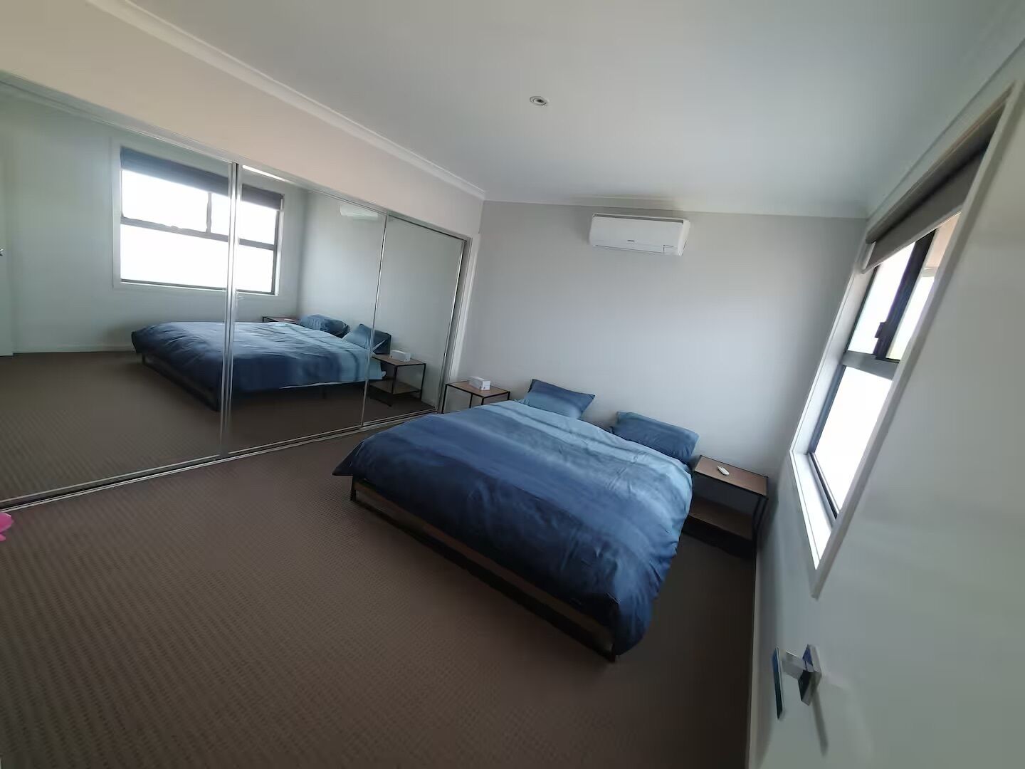 Un dormitorio con una cama grande, una mesita de noche, un espejo y una ventana.