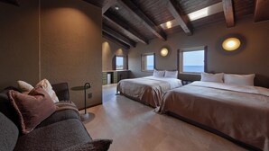 Habitación de hotel con dos camas, zona de estar y vista al mar.