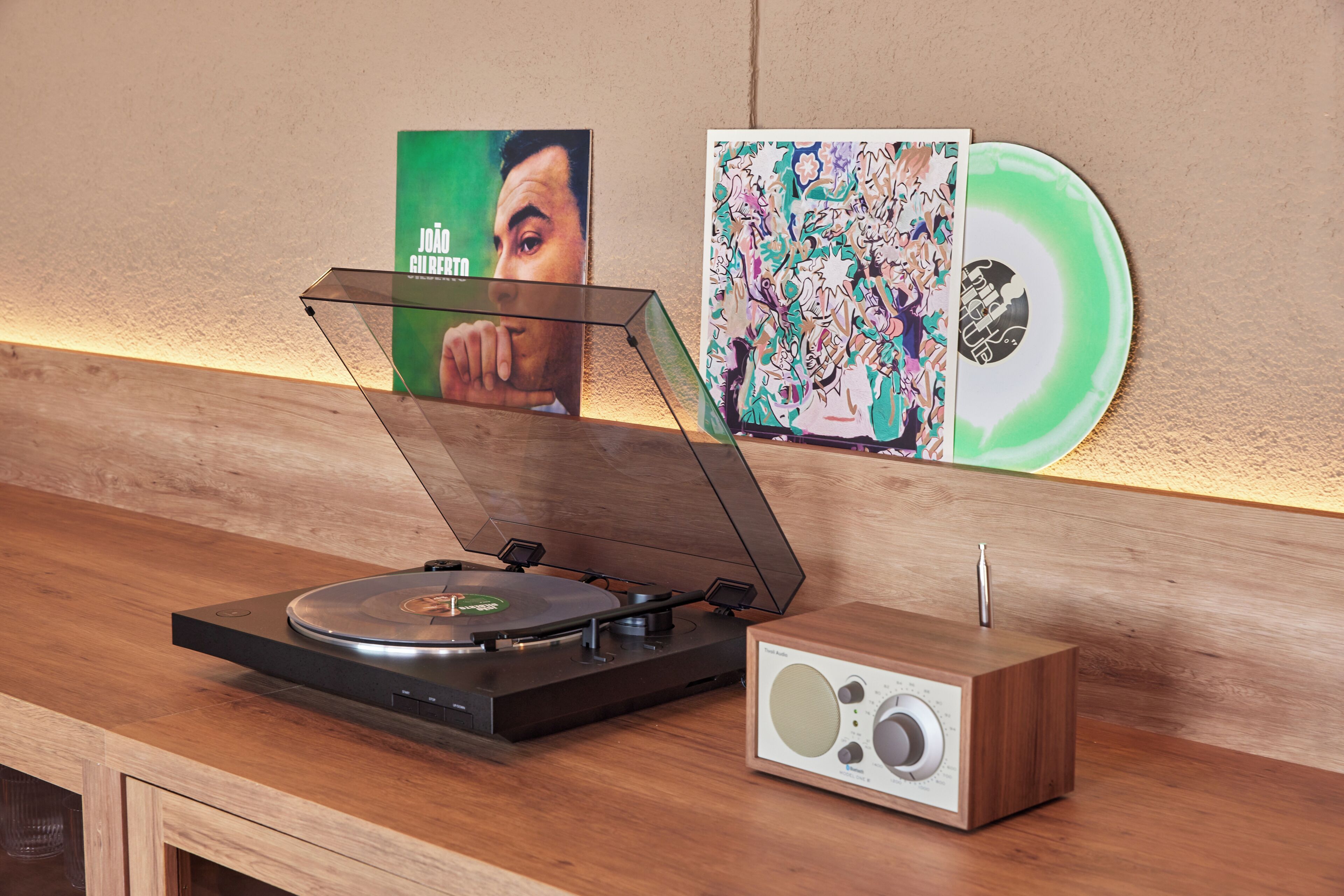 A turntable with a record, a speaker, and a wall with two posters.