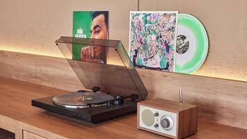 A turntable with a record, a speaker, and a wall with two posters.