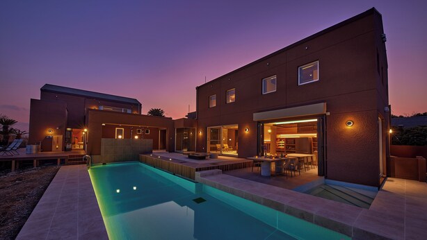 Una casa moderna con piscina, mobiliario de exterior e interior luminoso.