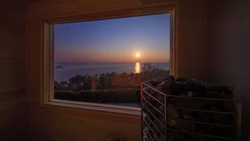 A window with a view of the ocean at sunset.
