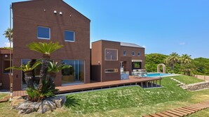 Una casa moderna de dos pisos con piscina, patio y césped bien cuidado.