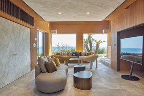 A modern living room with a sofa, coffee table, and a view of the sea.