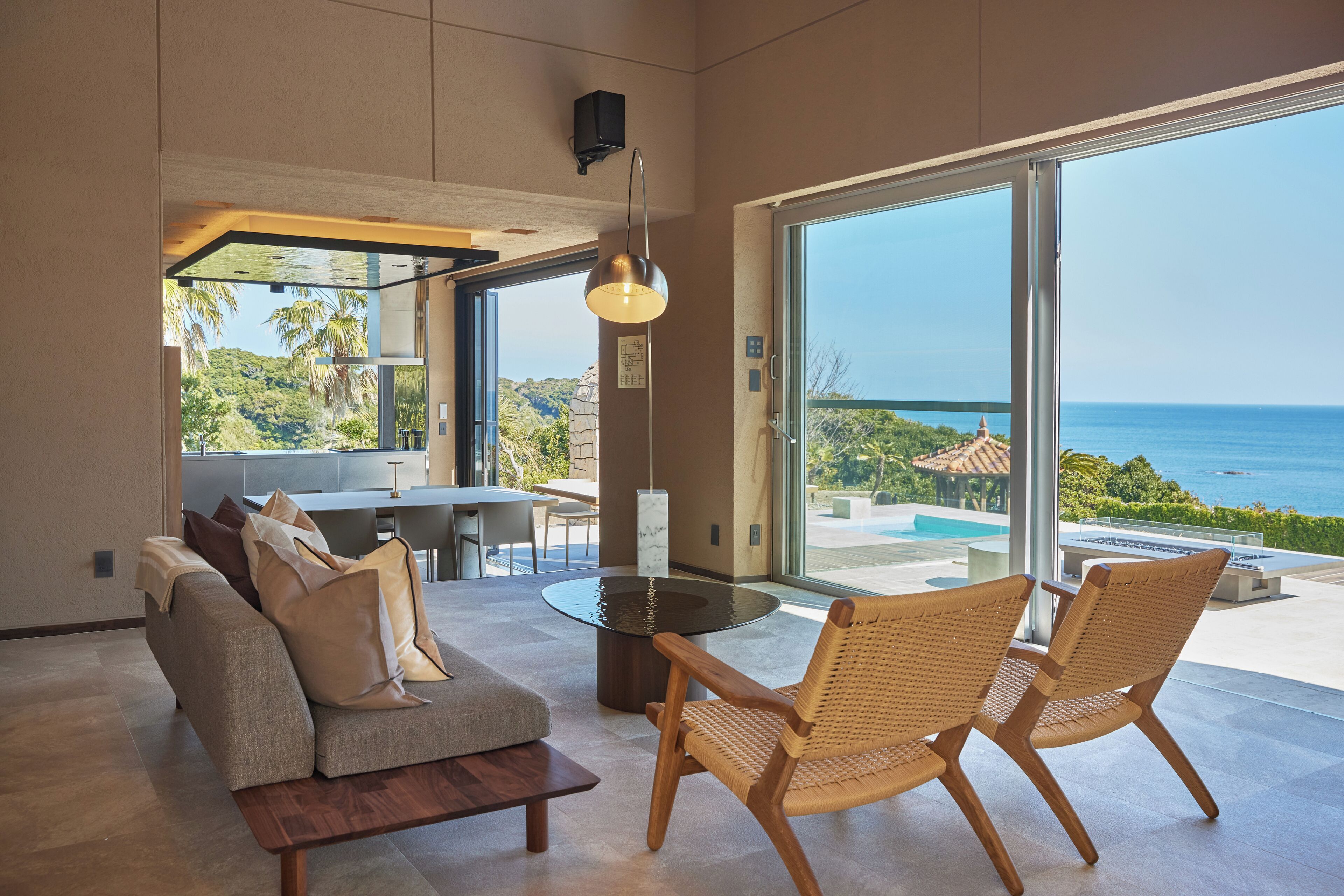 A modern living room with a sofa, chairs, a coffee table, and a view of the ocean.