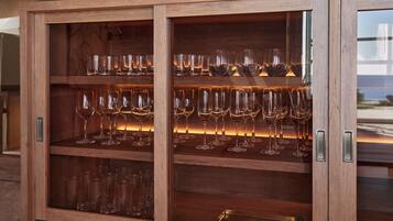 A wooden cabinet with multiple shelves containing wine glasses and tumblers.