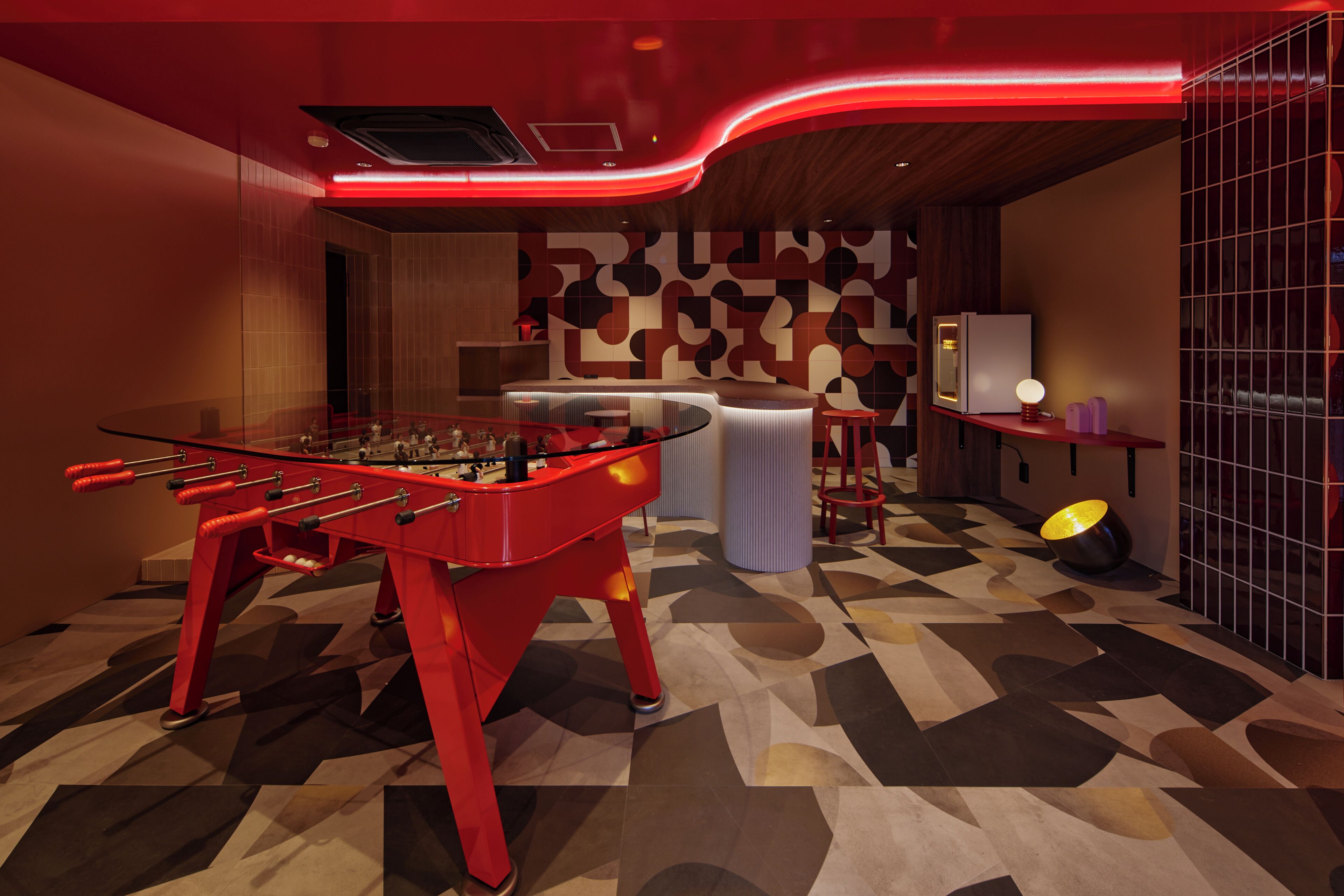 Quarto moderno com mesa de futebol, espaço de bar e parede estampada.