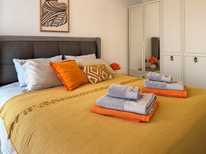 A neatly made bed with a patterned headboard, a bedside table with a lamp, and a wardrobe with a mirror. - Qoople Elize B26 - Cozy 1-bedroom apartment in gorgeous Alanya (Alanya)