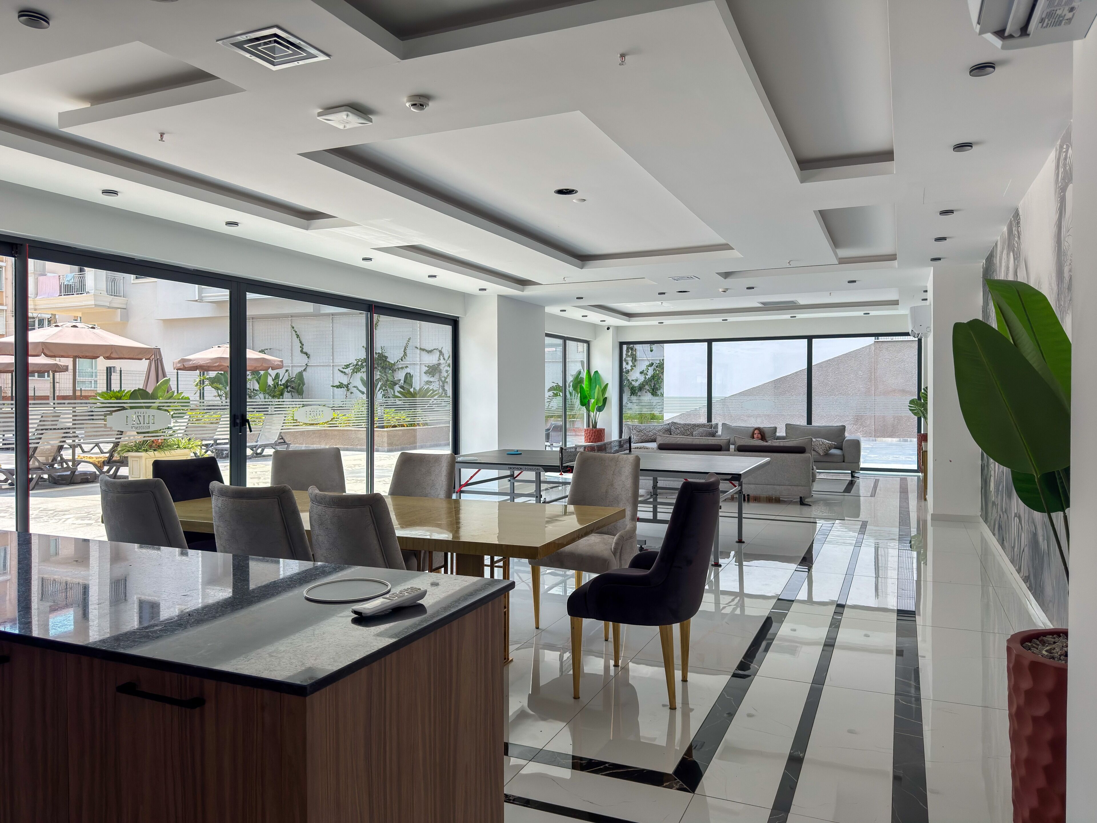 Eine moderne Hotelhalle mit einer Rezeption, einer Sitzgelegenheit und großen Fenstern mit Blick auf die Straße und die umliegenden Gebäude.